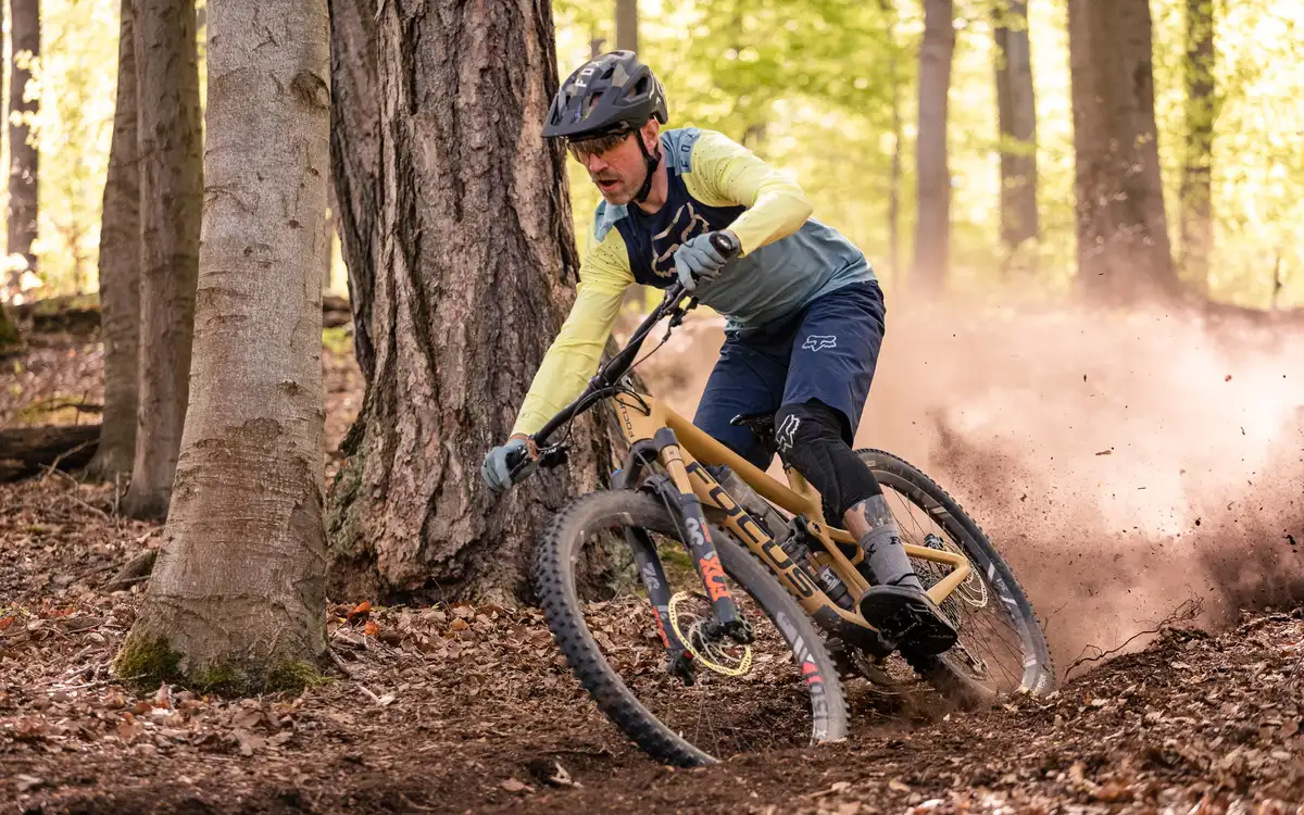 Enduro rider cornering in the woods and kicking up dirt