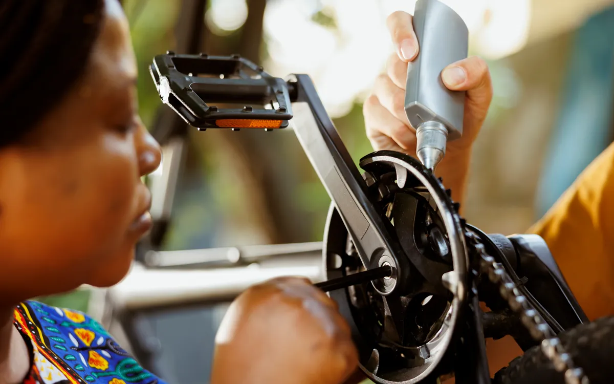 Cyclist lubricating the pedal and crank arm of their bike
