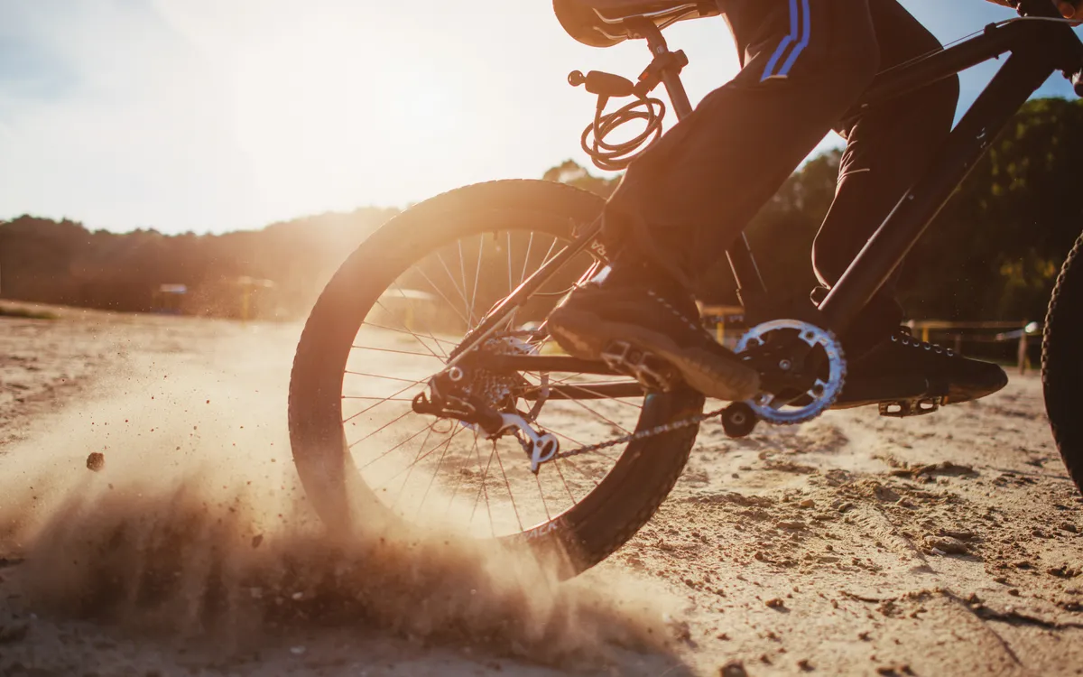 MTB rear wheel kicking up dust at sunset
