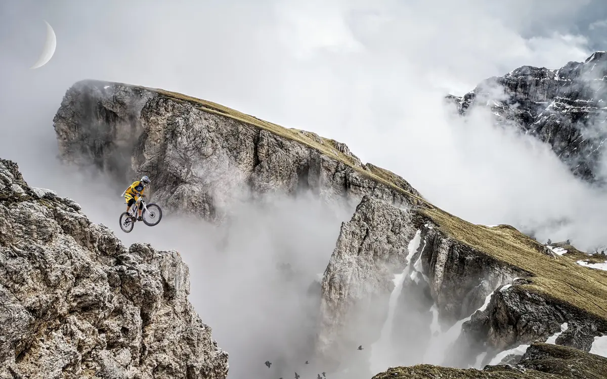 Mountain biker jumping over a clifftop in the mist