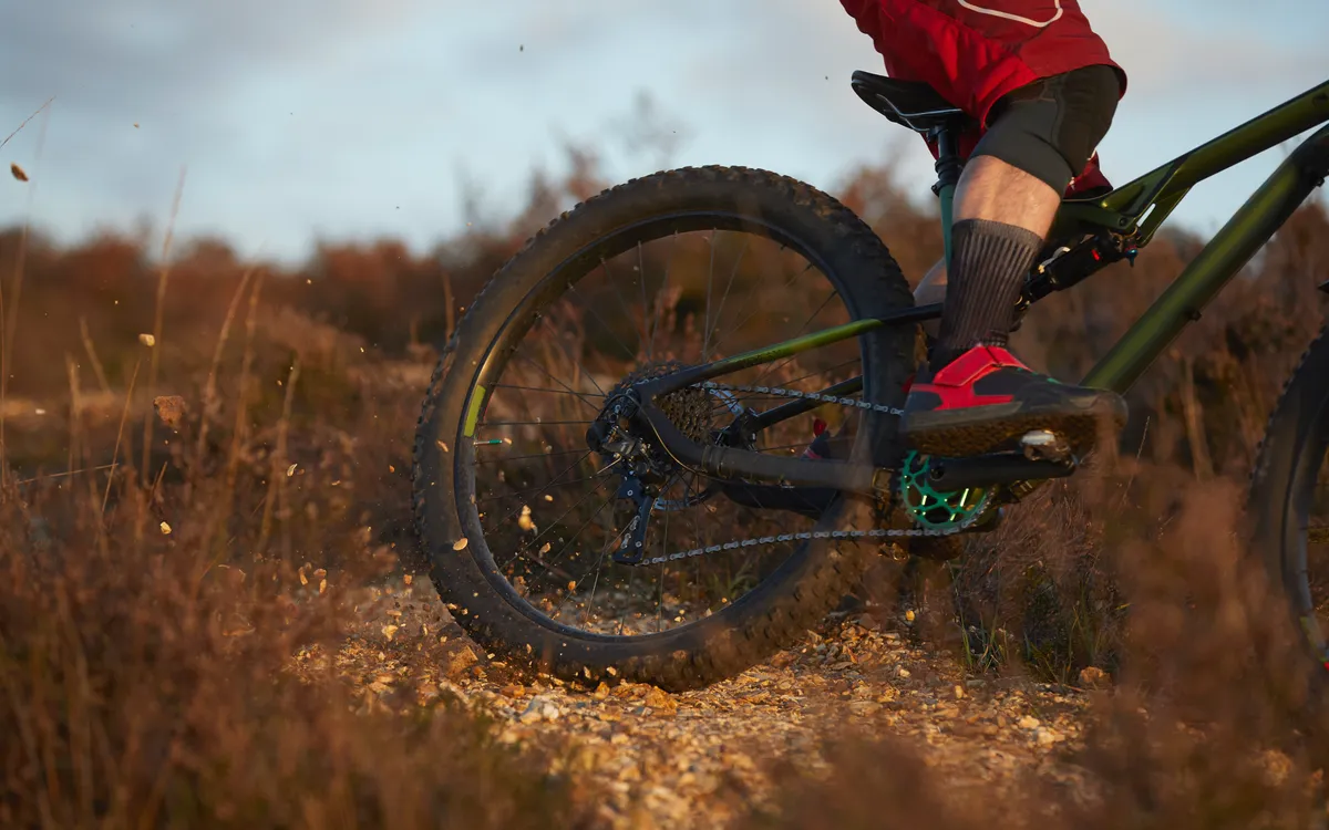 Cycling shoe clipped into a clipless pedal on a mountain bike skidding across gravel